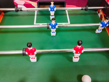 Friends having fun together playing foosball. Colleagues playing table football on break. Office people enjoying table soccer game. Close up of table football kicker gameの写真素材