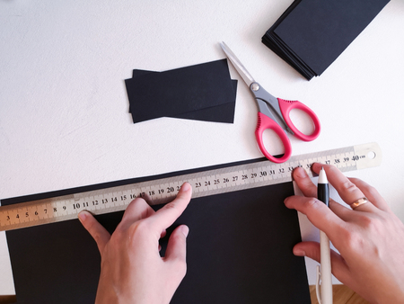 Close up shot - professional woman decorator, designer working with kraft paper and making envelope at workshop, studio. Design, handmade and art concept. Girl works at homeの写真素材