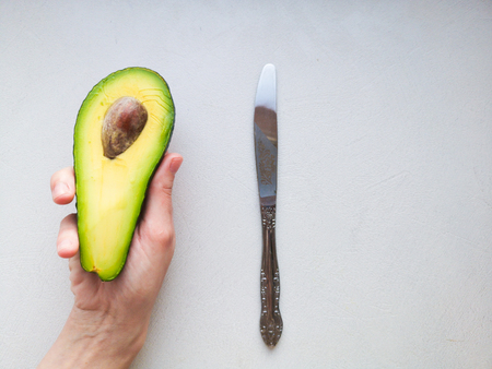 Avocado in hand, on white background. Man Proposing To Woman With Engagement Ring In Avocado. Closeup. Cut avocado.の写真素材