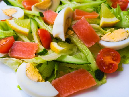 Closeup view of plate full of fresh green salad with mint leaves, yellow corn, tomato, tuna fish served with juicy lemon sauce. Person eats healthy foodの写真素材