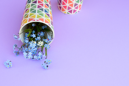 Flowers in a glass on a purple background. Fresh cut purple lilac flowers. colorful dishes, blooming flowers. Copy space.の写真素材