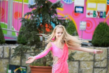 A young girl in pink is dancing. Smiling dancing. Dancing in the street. In the costume dancingのeditorial素材