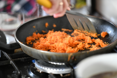 Grated carrots with onions in a skillet for frying.の写真素材