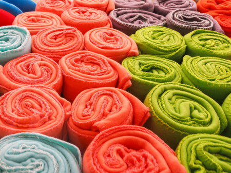 multi-colored towels rolled into a tube lie on each other on the shelf
