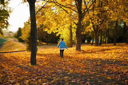 The girl runs into the autumn park. Running woman runner sunny bright light on the background of the...