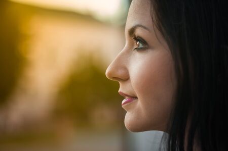 Young beautiful girl looks in profile, close-up. Profile portrait of a beautiful young woman looking at a warm pagoda from the window. Close up on the face, the joy of the solar pagodaの写真素材