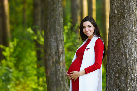 pregnant girl in red dress. Portrait of beautiful pregnant woman in red dress in the flowering...