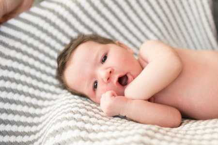 yawning child. Sleepy yawning baby with hands up in parents bedroom.