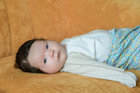 Baby lying on the couch. family, parenthood and motherhood concept - close up of mother playing with...