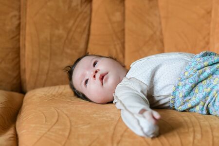 Baby lying on the couch. family, parenthood and motherhood concept - close up of mother playing with little baby daughter lying on sofa at home.の写真素材