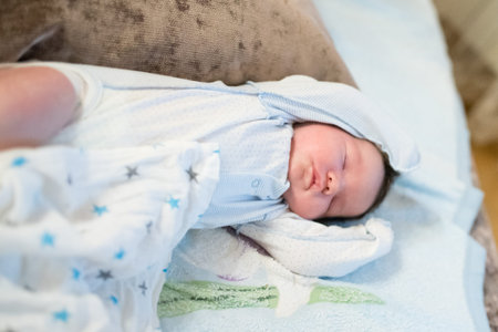 newborn baby sleeps with arms raised. A two week old baby boy, fast asleep with his arms raised