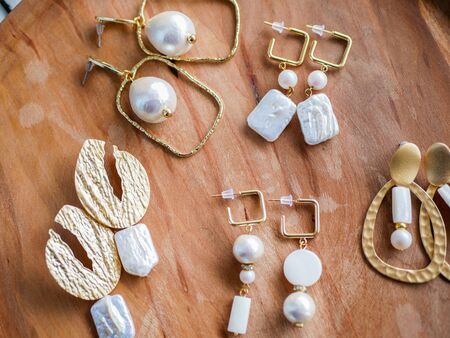 Gold earrings. Women's jewelry. Vintage decoration background. Beautiful golden tones brooches, bracelets, necklaces and earrings on a wooden tray. Flat lay, top view.の写真素材