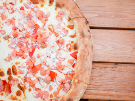 pizza with red fish and ham. divided into two components. the dough is cooked in a clay oven. on a wooden table. Close up of italian pizza. Ham, bacon, yellow cheese, tomato sauce. Top view, flat lay.の写真素材