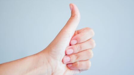 fingers on a gray background. hand with thumb up on gray background.の写真素材