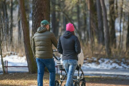 stroller walk in the winter park. Mother walks with a stroller on a snowy winter day. A young mother walks with a stroller on a snowy winter day .のeditorial素材