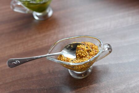 mustard in a glass bowl. French grain mustard in a bowl. French grain mustard in a glass bowl on white wooden table.の写真素材