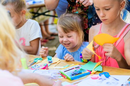 MOSCOW, RUSSIA - April 24, 2019: children and adults at the table do needlework and paint on the street on a sunny day. children's Day. developing club for children with disabilitiesのeditorial素材