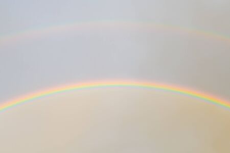 Two rainbows in the sky. Bright rainbows dancing in the light air clouds above and the foggy sky after rain below. natural shotの写真素材