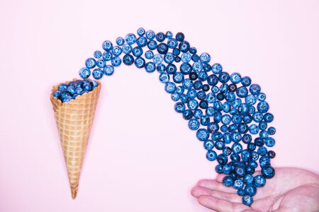 Berry ice cream. Blueberry in a horn. On a background for an inscription. hand and ice cream. top view vitamins concept. place for an inscription. berry love conceptの写真素材