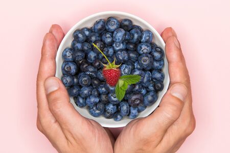 blueberries in the hand. Blueberries in hands on a colored background. place for writing. view from aboveの写真素材
