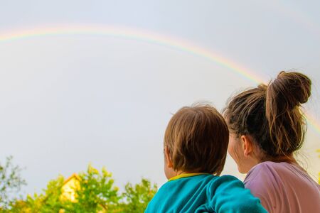 Mom with a child looks at the rainbow. Mom and son on the background of motherhood. Look at the rainbowの写真素材