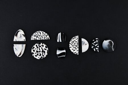 A product from polymer clay. Black and white polymer clay. Hand sculpting, product for earrings on a black background. View from above. Black and white jewelry earrings. Handmade polymer clay jewelry.の写真素材