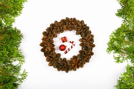 Handmade wreath of cones on a white background. decorated with needles to the side. Handwork. preparing for christmas. place for writing. View from above. Christmas wreath with fir cones on white background. Top Viewの写真素材