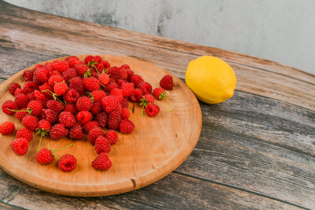 Raspberries with lemon on a wooden background. Wooden blocks with the words Vitamin C, fresh fruits...