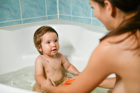 Joint bathing baby and mom. Moms hands wash the girls in the bathroom. A symbol of cleanliness and...