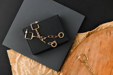Gold earrings. asymmetry. Close-up. Laid out on a wooden stand. View from above. The concept of jewelry and jewelry. Gifts for women. shopping. Handworkの写真素材