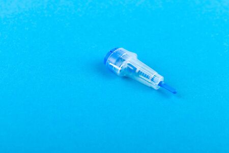 Childrens scarifier for taking blood. The device in the blood sample of the child. On a blue background. blood test with a finger of a child. injection of blood from a childs fingerの写真素材