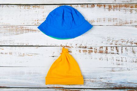 Baby hats on a wooden background. Blue Panama. yellow hat white wooden table. view from aboveの写真素材