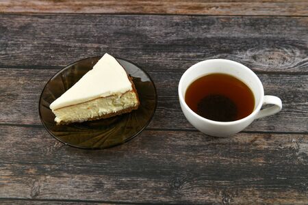 Cheesecake with coffee on a dark wooden background. view from above. A cheesecake next to it on a brown wooden background. retro cup. Coffee in a coffee shop, copy spaceの写真素材