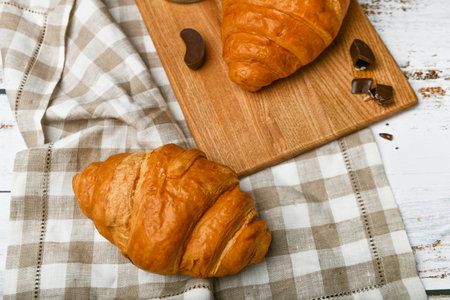 chocolate croissants. the beginning of the morning. A cup of coffee. Fresh french croissant. Coffee cup and fresh baked croissants on a wooden background. View from aboveの写真素材