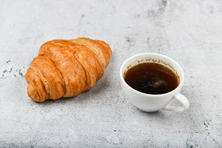 croissant and cup. on a specific background. Fresh french croissant. on a wooden background. View from above. Morning breakfast with a croissant. A French breakfast is prepared at home. on the stove and cup of espresso.の写真素材