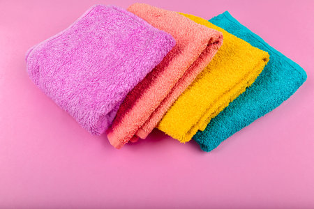 Multi-colored towels on a pink background. Pink, beige, yellow and blue flower towels. Place for writing. House orderの写真素材
