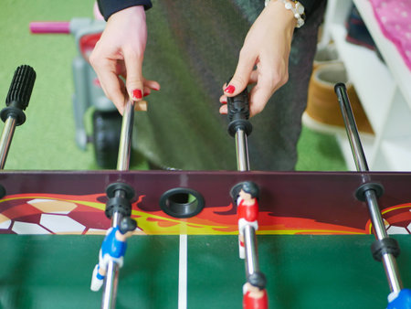 A girl plays table football. A game of table football. Entertainment for the company. Young people from the office enjoy playing table football in their free time at the workplaceの写真素材