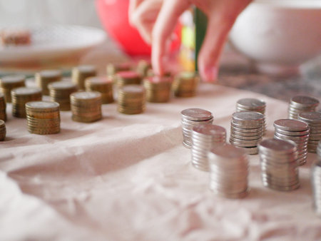 Hand and a lot of coins. Counting savings. Tax rate. Production costs. Distribution of finance