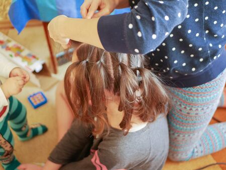 A mother is combing her baby. Mother caring for a child combing hair at home in the bedroom. maternal care.の写真素材