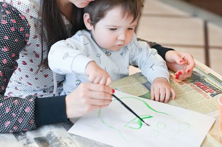A child draws on his mothers lap. The child sits on his lap with his mother and draws gouache. Dusseldorf, Germany - October 11, 2019のeditorial素材