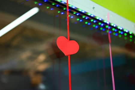 Red paper heart hanging on a rope. Valentine heart with bow hanging on a rope. St. Valentines Day.