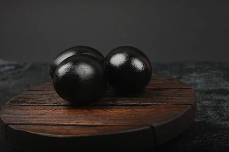 black eggs on a wooden board. flat lay. Black Easter. three black eggs.の写真素材