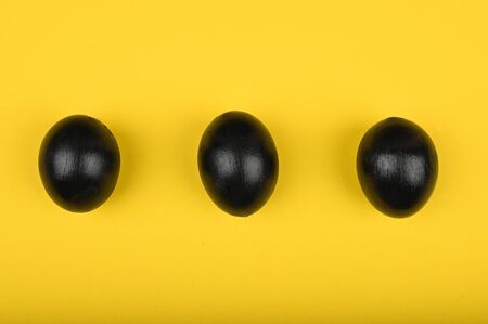 Three fried eggs on a yellow background. flat lay. Black Easter. three black eggs.の写真素材