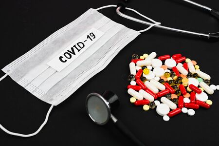 Disposable medical face mask, pills,stethoscope and a blood in the test tube on a black background. Pandemic Coronavirus Concept.の写真素材
