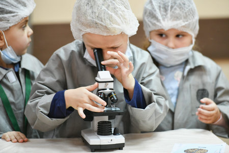 The baby is looking through a microscope. Teaching medicine. Young doctors at a seminar in a hospital. Children and medicine KHARKIV, UKRAINE - JANUARY 20, 2020.のeditorial素材