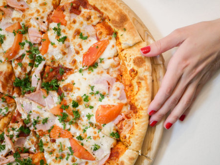 Female hand and pizza. kind of pizza with bacon tomatoes and herbsの写真素材