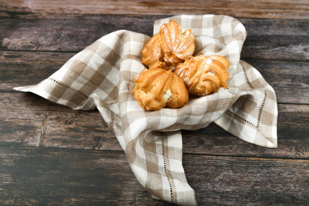 Choux cake on a wooden background. In a basket on a checkered towel. The apartment was lying. View...