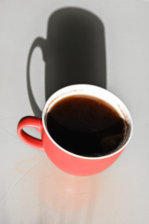 red cup with a shadow. Long shadow from a cup of coffee.の写真素材