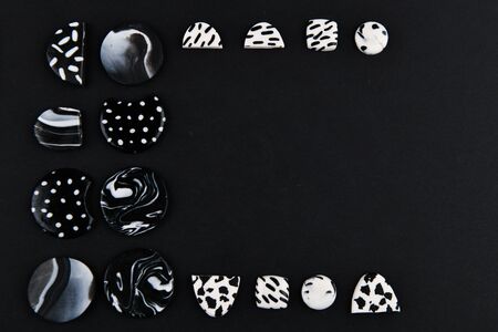 A product from polymer clay. Black and white polymer clay. Hand sculpting, product for earrings on a black background. View from above. Black and white jewelry earrings. Handmade polymer clay jewelry.の写真素材