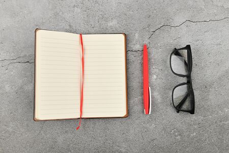 black notebook and red pen. Blank notebook and red pen. Blank notebook and red pen on gray concrete background. view from aboveの写真素材